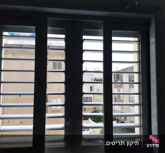תריסים לבנים פתוחים עם נוף בניינים ברקע